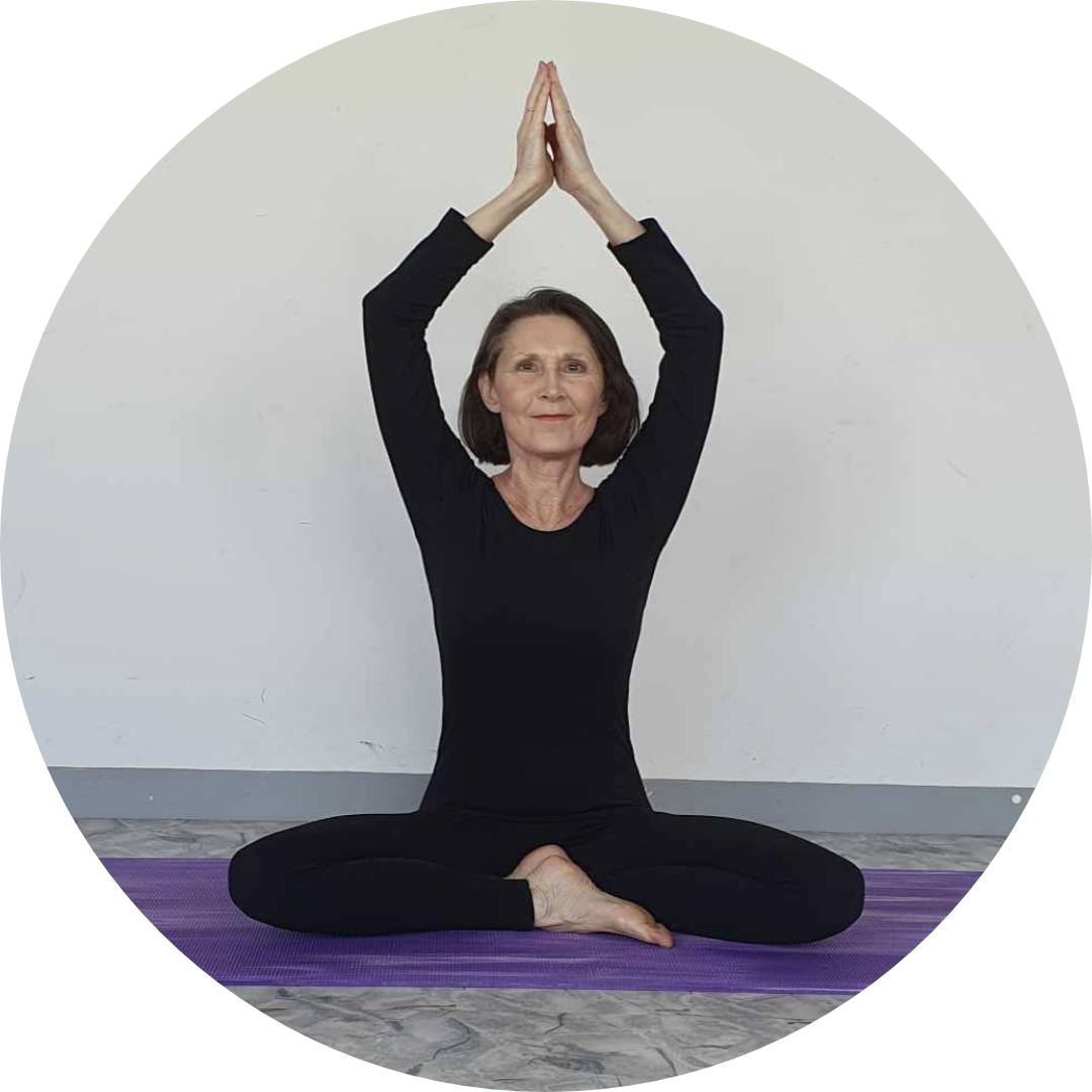 Gabrielle Brousse, professeure de yoga, effectue la posture en tailleur, bras en l'air.